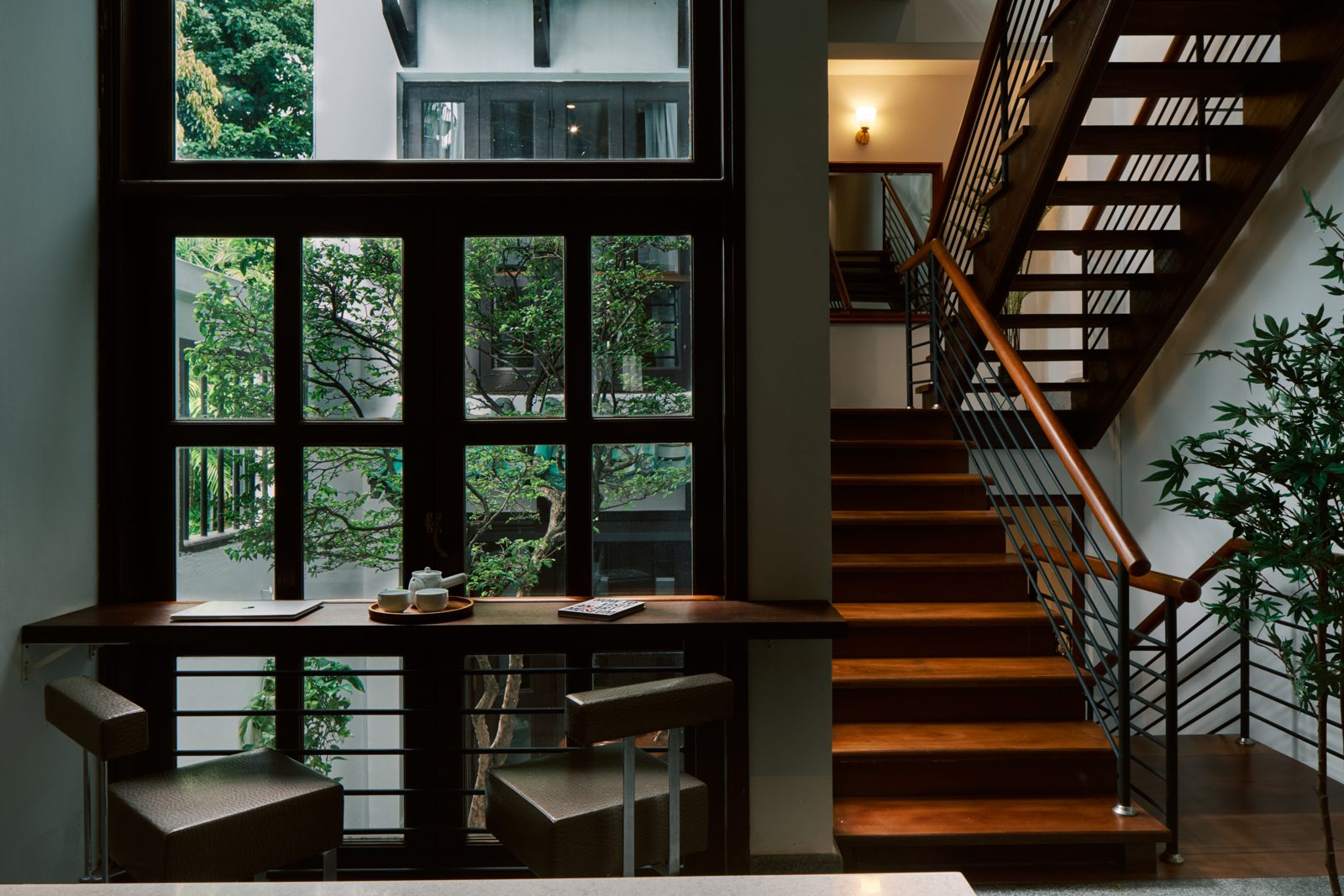Existing Kongsi House interior with tall windows, greenery and stairs